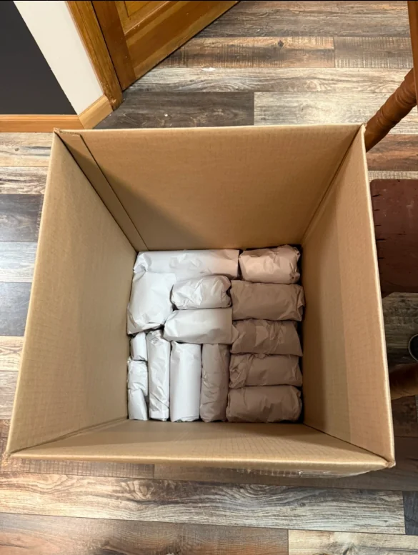 Individually wrapped household items arranged in a cardboard moving box